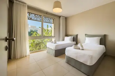 two beds in a room with a large window at Remarkable & Rare 2BDR Mangroovy Free Pool & Beach in Hurghada