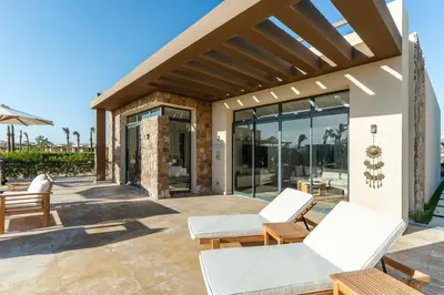 a patio with white chairs and a building with glass doors at Modern luxury villa in SomaBay in Hurghada