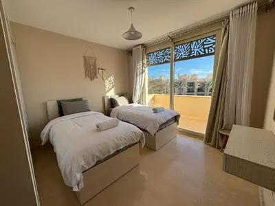 a bedroom with two beds and a large window at El gouna mangrouovy in Hurghada