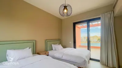 two beds in a bedroom with a window and a chandelier at Ollystays Tawila 3BR Townhouse Shared Pool in Hurghada