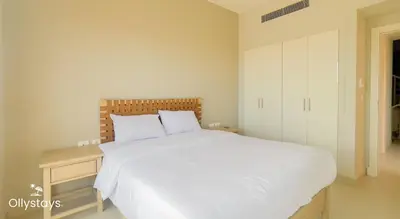 a bedroom with a large white bed and a night stand at Ollystays Tawila 3BR Townhouse Shared Pool in Hurghada