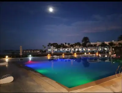 a large swimming pool at night with the moon overhead at Scandic Resort Hurghada, Sea View in Hurghada