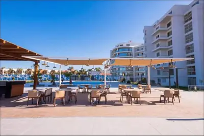 a patio with tables and chairs and a large umbrella at Scandic Resort Hurghada, Sea View in Hurghada