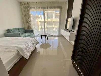 a bedroom with a bed and a couch and a television at Studio el Gouna holiday G cribs Compound in Hurghada