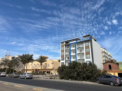 a building on the side of a street with cars parked at البلكان بيتش ريزورت Balkan Beach Resor in Hurghada