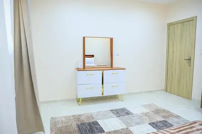 a bedroom with a dresser with a mirror and a door at Peaceful Magawish Apartment in Hurghada
