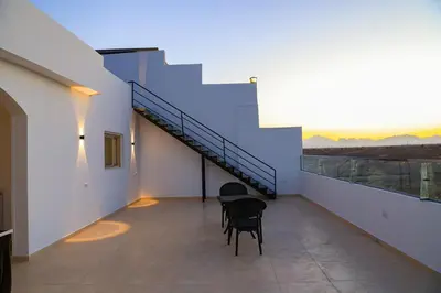 a balcony with chairs and a staircase on a building at Peaceful Magawish Apartment in Hurghada