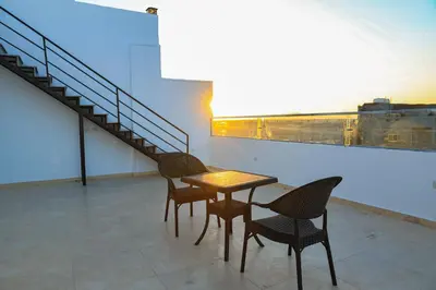 a table and chairs on a roof with a staircase at Peaceful Magawish Apartment in Hurghada