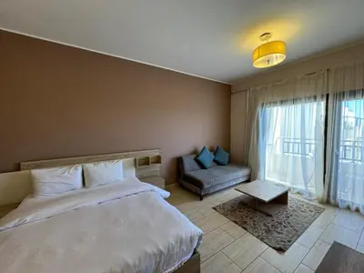 a bedroom with a bed and a couch and a window at Aldau Heights in Hurghada