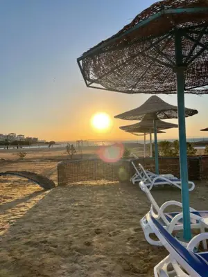 a group of chairs and an umbrella on a beach at Hurghada Fiesta Resort Studio 323 in Hurghada