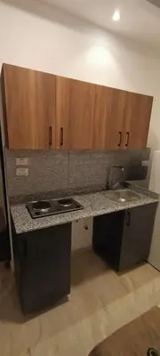 a kitchen with a counter top and wooden cabinets at Hurghada Fiesta Resort Studio 323 in Hurghada