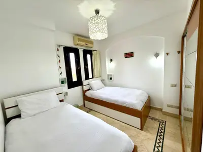 a bedroom with two beds and a chandelier at Exquisite 1BR Chalet with Pool and Beach Front El Gouna in Hurghada