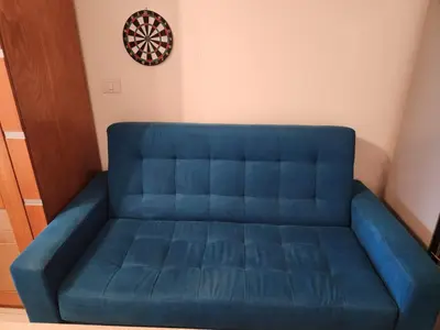 a blue couch in a room with a dartboard on the wall at Studio for rent in Hurghada 116 in Hurghada