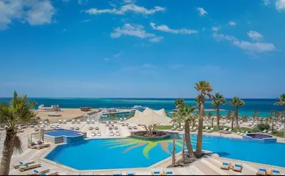 a large pool with chairs and palm trees and the ocean at Hurghada in Hurghada
