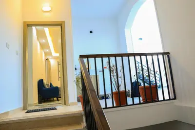 a hallway with a staircase with a mirror and a chair at Peaceful Magawish Apartment in Hurghada