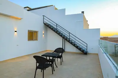 a room with a table and chairs and stairs at Peaceful Magawish Apartment in Hurghada