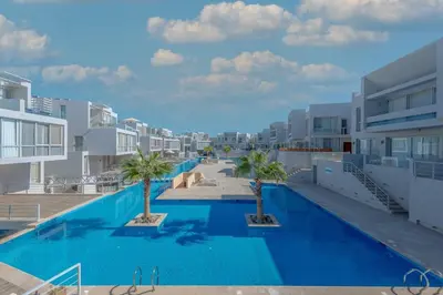 a swimming pool with palm trees in front of buildings at Modern 1BR with Pool View in Sholan El Gouna in Hurghada
