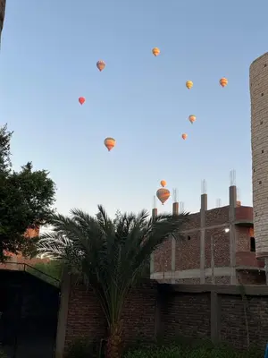 three kites flying in the sky over a brick building at Tokyo House Luxor in Luxor