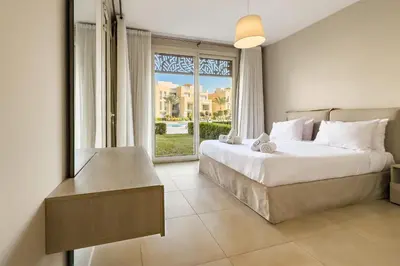 a bedroom with a bed and a large window at Modish & Modern 1BDR Poolfront Mangroovy Free Pool & Beach in Hurghada