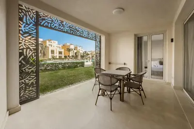 a dining room with a table and chairs and a large window at Modish & Modern 1BDR Poolfront Mangroovy Free Pool & Beach in Hurghada