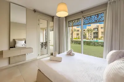 a bedroom with a large white bed and a large window at Modish & Modern 1BDR Poolfront Mangroovy Free Pool & Beach in Hurghada
