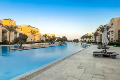 a swimming pool in a resort with palm trees at Modish & Modern 1BDR Poolfront Mangroovy Free Pool & Beach in Hurghada