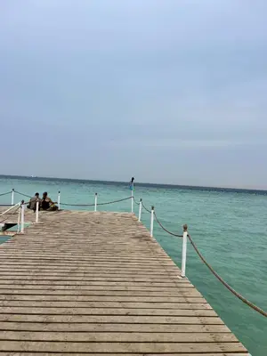 two people sitting on a dock in the water at Scandic Resort Hurghada in Hurghada