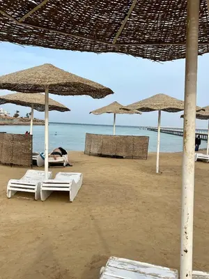 a person laying on a beach with umbrellas at Scandic Resort Hurghada in Hurghada