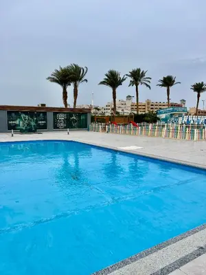 a large blue swimming pool with palm trees in the background at Scandic Resort Hurghada in Hurghada