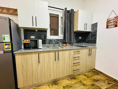 a kitchen with wooden cabinets and a microwave at Cleopatra Style City Center in Hurghada