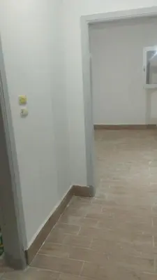 a room with a white wall and a tile floor at منزل خاص غرفتين 2 حمام صاله مطبخ امريكي جنينه خاصه سلم خارجي رووڤ in Al Aqālitah