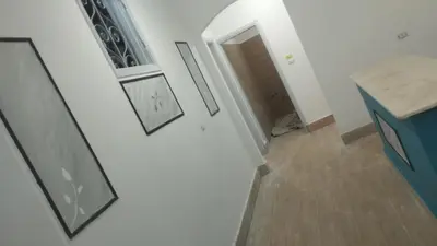 a hallway with two pictures on the wall and a table at منزل خاص غرفتين 2 حمام صاله مطبخ امريكي جنينه خاصه سلم خارجي رووڤ in Al Aqālitah