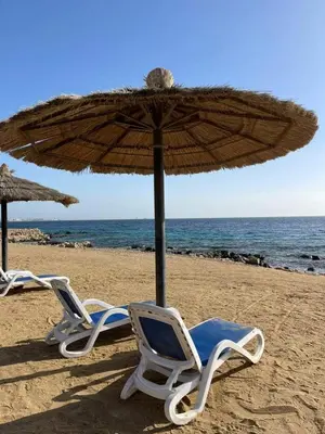 two chairs and an umbrella on a beach at Studil for rent in the view 608 in Hurghada