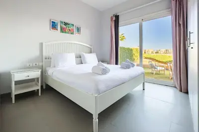 a white bedroom with a bed and a large window at The 2BDR Warmhearted Waterside Apt in Hurghada