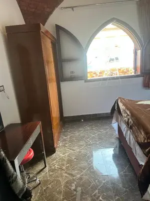 a bedroom with a bed and an arched window at ZAIN PALACe in Jazīrat al ‘Awwāmīyah