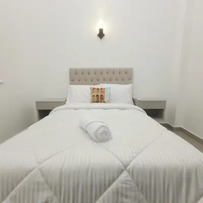 a white bed with a white blanket on it at Oasis Apartment in Safaga