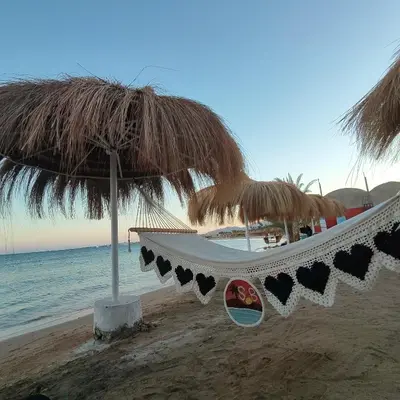 a hammock under a straw umbrella on the beach at Oasis Apartment in Safaga