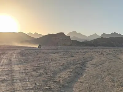 a person riding a motorcycle in the desert at sunset at Oasis Apartment in Safaga
