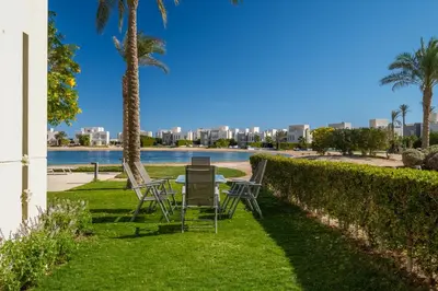 a table and chairs in the grass next to a body of water at Joubal 2BR • Premium Ground Floor in Hurghada