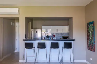 a kitchen with a bar with four bar stools at Joubal 2BR • Premium Ground Floor in Hurghada