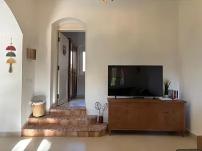 a living room with stairs and a television on a dresser at Cozy 1BR in the Heart of Gouna in Hurghada