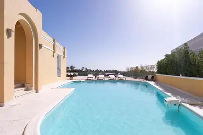 a swimming pool with chairs on the side of a building at Luxury 5BD Villa with Pool in Hurghada