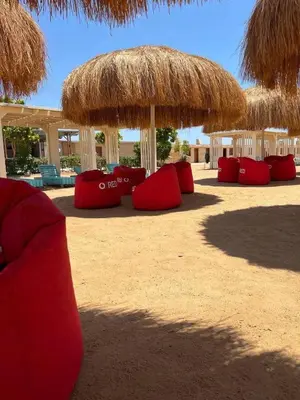 a group of red chairs and umbrellas on the beach at Alhambra Avenue in Hurghada
