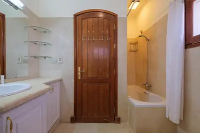 a bathroom with a wooden door and a sink and a tub at Serene 4BR Villa • Authentic West Golf in Hurghada