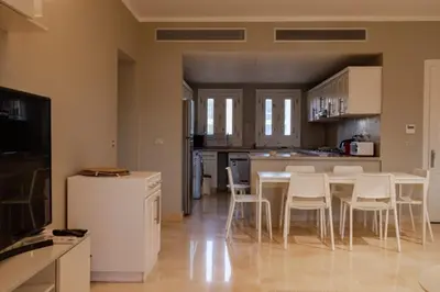 a kitchen with a table and white chairs in a room at 2BR New Marina Bliss • Cozy Centered Stay in Hurghada