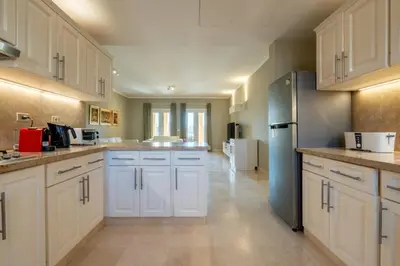 a large kitchen with white cabinets and a blue refrigerator at 2BR New Marina Bliss • Cozy Centered Stay in Hurghada