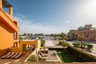 a balcony of a building with lounge chairs and a marina at 2BR New Marina Bliss • Cozy Centered Stay in Hurghada