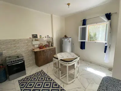a kitchen with a refrigerator and a table in it at Asmara Apartment Hatshepsut in Naj‘ al Madāmūd