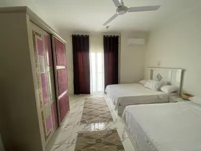 a hotel room with two beds and a ceiling fan at Asmara Apartment Hatshepsut in Naj‘ al Madāmūd