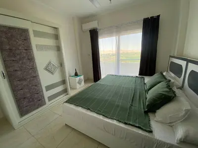 a bedroom with a large bed and a large window at Asmara Apartment Hatshepsut in Naj‘ al Madāmūd